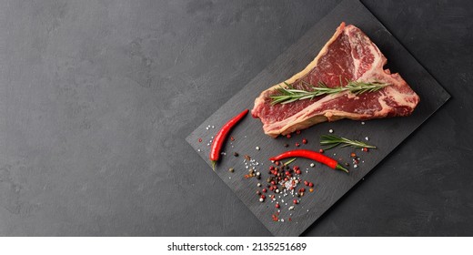 Raw Beef Steak, Dry Aged T Bone With Red Hot Pepper And Spices On Black Background, Top View. Free Space For Text