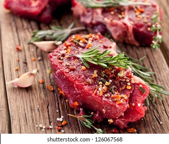 Raw beef steak on a dark wooden table.