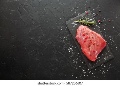 Raw Beef Steak With Rosemary And Peppers On Dark Stone