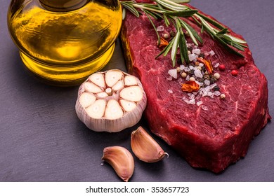 Raw Beef Steak, salt, pepper, garlic, rosemary  on the black board, background.  - Powered by Shutterstock