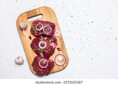 Raw beef steaks fillet mignon on the wooden board with herbs and spices on white stone background top view, copy space for your design. - Powered by Shutterstock