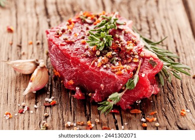 Raw beef steaks with herbs and spices ready for cooking are on wooden board. - Powered by Shutterstock