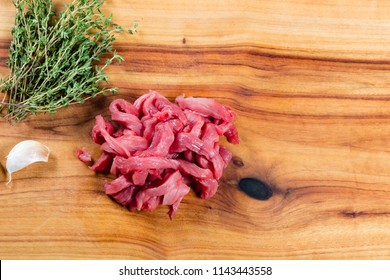 Raw Beef Strips On Chopping Board With Herbs
