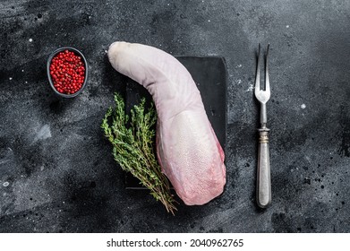 Raw beef or veal tongue on marble board with thyme. Black background. Top view