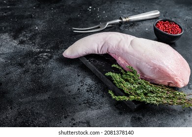 Raw beef or veal tongue on marble board with thyme. Black background. Top view. Copy space