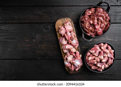 Raw bird giblets raw poultry meat set, on black wooden table background, top view flat lay, with copy space for text