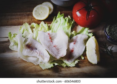 Raw Bluegill Fillets With Fresh Tomatoes, Lettuce And Lemons