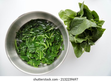 Raw and boiled spinach on a white background. shocking was done in ice water. blanching - Shutterstock ID 2132239697