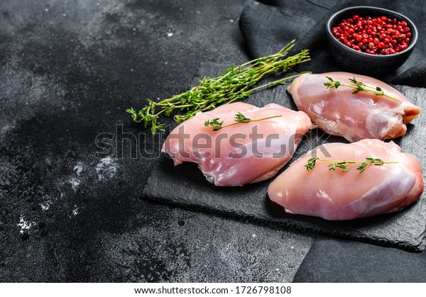 Raw boneless chicken thighs fillet. Black\
background. Top view. Copy\
space