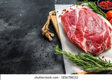Raw brisket beef cut on a wooden cutting board. Black Angus beef. Black background. Top view. Copy space
