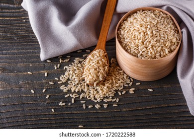 raw brown rice on dark rustic wooden background