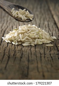 Raw Brown Rice In Spoon On Wooden Background