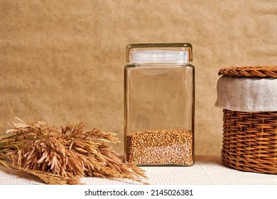 Raw buckwheat, ears of wheat and a basket on the rural kitchen table. Traditional food and cooking