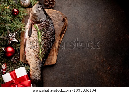 raw carp for preparation for the holiday Christmas on a background of stone with Christmas trees and Christmas decorations 
with copy space for your text