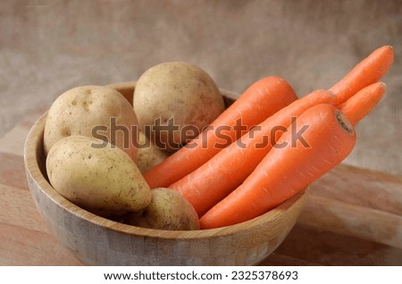 Raw Carrot and potatoes in wooden basket bowl