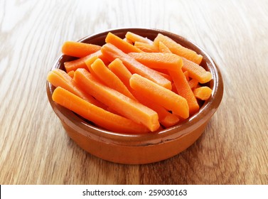 Raw Carrot Sticks In Brown Rustic Bowl On Wooden Table