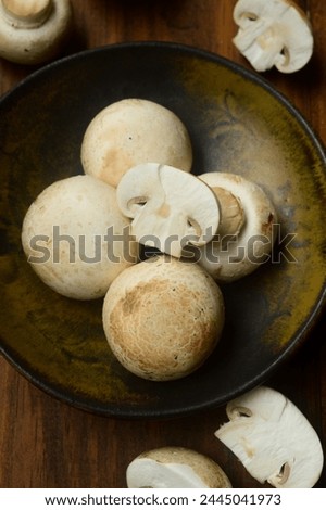 Raw Champignon Mushrom (Jamur Kancing) on wooden background. Top view. 