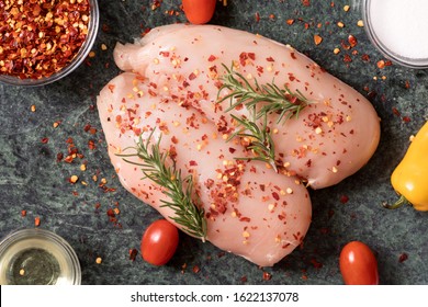raw chicken breast with rosemary, vegetables  and red pepper on green marble cutting board. Top View of Chickenbreast