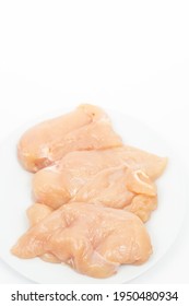 Raw Chicken Breasts On The Plate Above White Background.