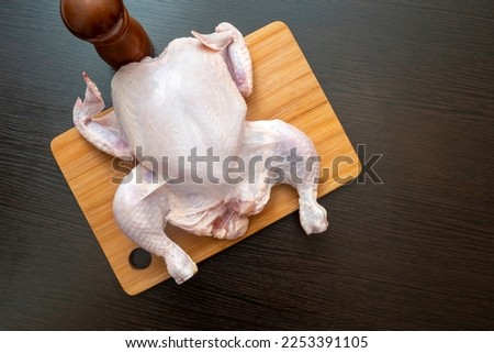 Raw chicken carcass on wooden table at a kitchen, top view