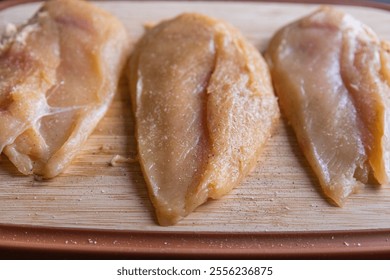 Raw Chicken Fillet Breast Seasoned on a Wooden Cutting Board – Close-Up - Powered by Shutterstock