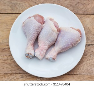 Raw Chicken Legs On A White Plate.