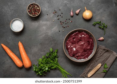 Raw chicken liver in bowl with spices, carrots, onions on dark grunge background. Top view, flat lay, frame. Place for your recipe - Powered by Shutterstock