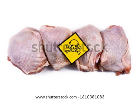 Raw chicken meat with yellow poisonous skull warning sign, concept for meat contaminated with bacterium, germs, antibiotics and other residue possibly harmful to human health