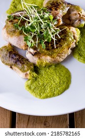 Raw Chicken On The Bone With Mung Bean Salad And Green Sauce On A White Round Plate. Vertical Orientation