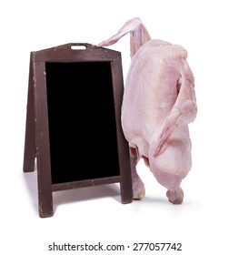 Raw Chicken Standing Next To A Black Chalkboard With Menu