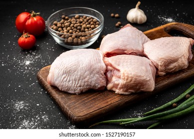 Raw chicken thigh on black background.