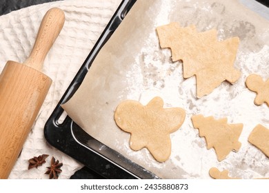 Raw Christmas cookies in baking tray, rolling pin and anise stars on table, flat lay - Powered by Shutterstock