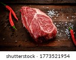 Raw Chuck Eye Roll beef Steak on a rustic wooden background with seasonings
