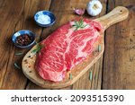 raw chuck eye steak on wooden board