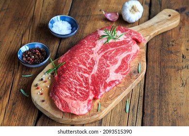 raw chuck eye steak on wooden board