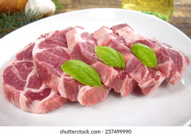 Raw Chuck Steak With Basil On White Plate