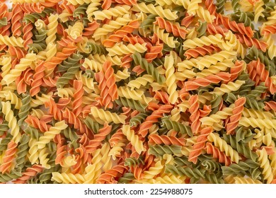 Raw colored pasta fusilli. Uncooked pastas background. Top view.