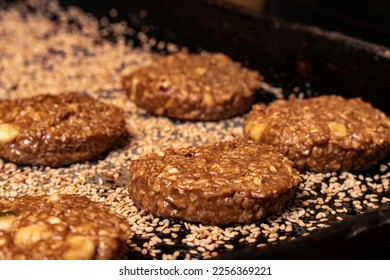 Raw cookie dough with banana and cashews on a black baking sheet with lots of sesame seeds - Powered by Shutterstock