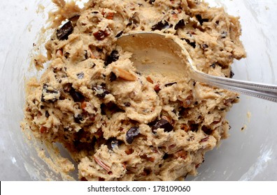 Raw Cookie Dough Being Mixed With Chocolate Chunks And Chopped Pecan Nuts