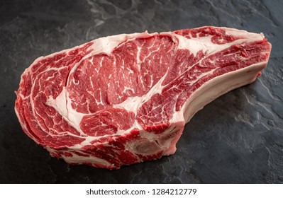 Raw Cowboy Steak On Stone Background, Prime Rib Eye On Bone