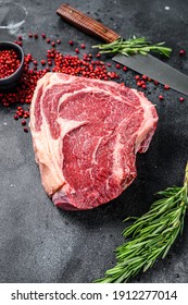 Raw Cowboy Steak Or Ribeye On The Bone With Herbs. Marble Beef. Black Background. Top View.