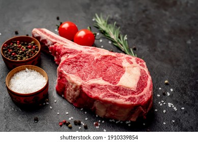 
Raw Cowboy Steak With Spices On Stone Background