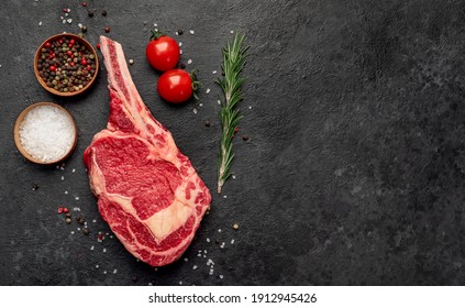 Raw Cowboy Steak With Spices On Stone Background