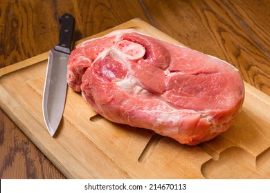 Raw Cut Of Pork Shoulder On Board With Knife