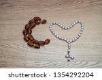 Raw dates in the shape of a crescent moon on oak wooden background and next to it is a sebha/bearish with it