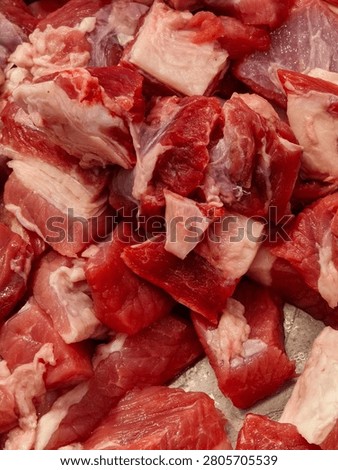 Raw diced beef chunks closeup. Freshly cut, marbled red beef pieces with rich white fat trimmings piled together, showcasing natural texture and vibrant crimson color perfect for culinary preparation.