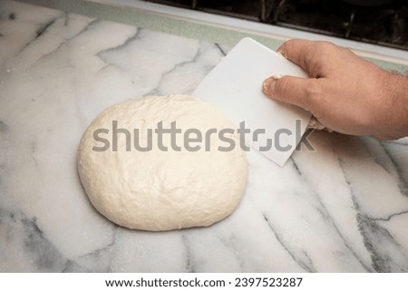 Raw dough ball is prepared and shaped by food scraper.