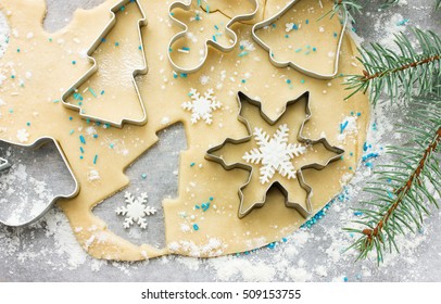 Raw dough for Christmas cookies and cookie cutters shaped glove, Christmas tree, snowflake, jingle bell, gingerbread man