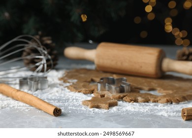 Raw dough, cookie cutters, pine cone, whisk and rolling pin on grey table, closeup - Powered by Shutterstock