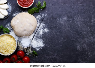 Raw Dough For Pizza With Ingredients And Spices On Black Background.overhead With Copy Space